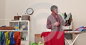 Caucasian man ironed clothes in laundry room. Tidy man ironing shirt at home, diligent husband doing household chores