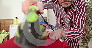 Caucasian man ironed clothes in laundry room. Tidy man ironing shirt at home, diligent husband doing household chores