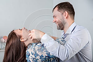 Caucasian man jokingly strangles a woman on a gray background