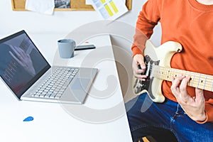 Caucasian man learning to play electric guitar with video lessons