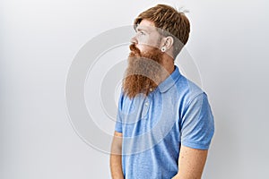 Caucasian man with long beard standing over isolated background looking to side, relax profile pose with natural face with