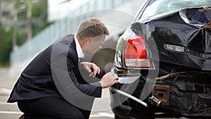 Caucasian man looking crashed auto after car accident, damage repair, insurance