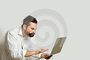 Caucasian man looking with displeasure angrily into laptop monitor Isolated on gray background. Side view. Human