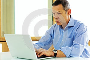 Caucasian man looking at his laptop computer