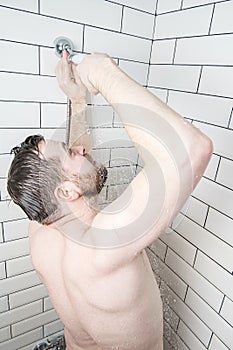 Caucasian man is trying to repair a watering can in a shower room that has broken or cold water has spilled out of it.