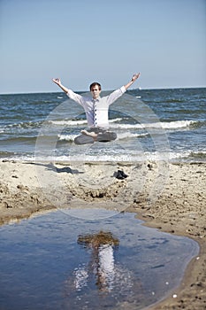 Caucasian man in lotos pose levitates above the beach