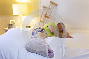 Caucasian man lying down in bed with broken foot