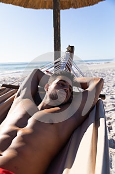 Caucasian man lying on a hammock at the beach.