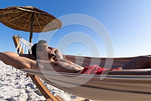 Caucasian man lying on a hammock at the beach.