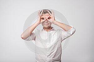 Caucasian man making sign of owl with hands.