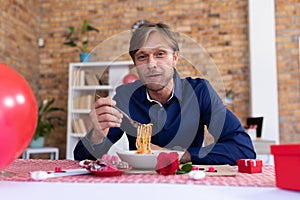 Caucasian man making video call sitting a table eating spaghetti