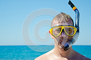 Caucasian man in mask with snorkel against background of blue sky and turquoise sea is ready to dive. Aquatic recreation concept.