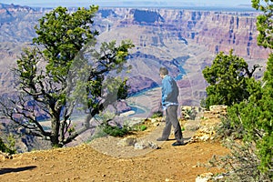 Caucasian man in mid forties cautiously looking over cliff at Gr