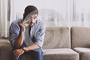 Caucasian man with mustache and beard talking with mobile phone in living room about serious problem