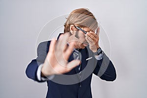 Caucasian man with mustache wearing business clothes covering eyes with hands and doing stop gesture with sad and fear expression