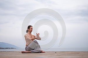 Caucasian man with naked torso practicing wushu on the seashore.