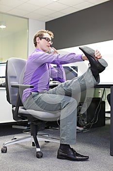 Caucasian man office worker with phone in hand, stretching legs