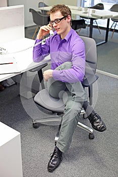 Caucasian man office worker with phone in hand, stretching legs