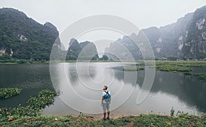 Caucasian man overlooking limestone mountains in Ninh Binh province, Vietnam. Cloudy day