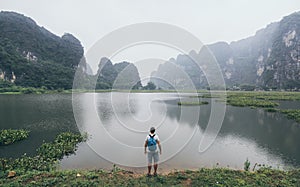 Caucasian man overlooking limestone mountains in Ninh Binh province, Vietnam. Cloudy day
