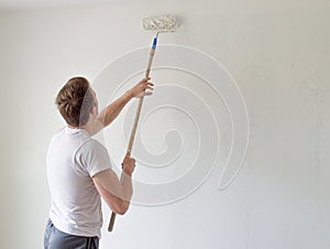 Caucasian man painting a wall with a paint roller