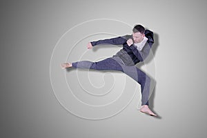 Caucasian man performing karate kick in the studio