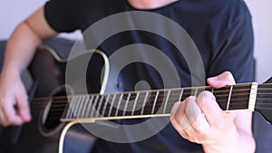 Caucasian man playing chords in a black acoustic guitar