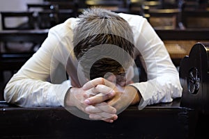 Caucasian man praying in church. He has problems and ask God for help