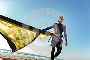 Caucasian man professional surfer standing on the sandy beach with his kite