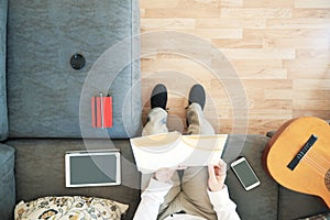 Caucasian man reading a book studying in the living room. Overhead shot from above and empty copy space