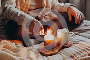 A caucasian man relaxing at home, lighting candle, drinking coffee in bed