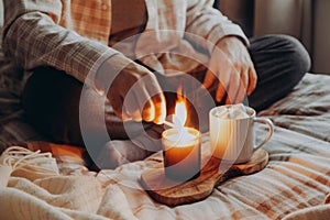 a caucasian man relaxing at home, lighting candle, drinking coffee in bed