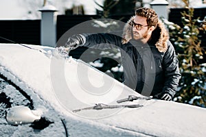 Caucasian man removes snow from vehicle, cleaning snow after blizzard photo