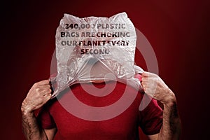 The caucasian man rips off the plastic bag from his head, suffocating. Red background. Copy space. Concept of pollution