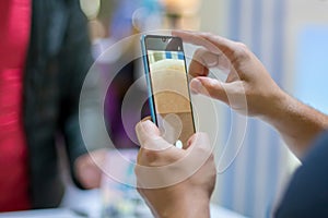 A caucasian man`s hands hold new flagship smartphone and test camera. close up, soft focus. background in blur