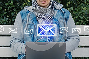 Caucasian man sits on a bench and scans email