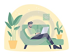 Caucasian man sitting on green sofa working on laptop at home. Casual remote work, cozy indoor setting with plants