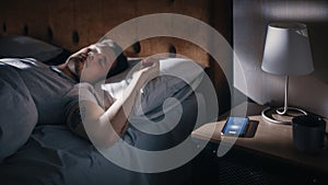 Caucasian Man Sleeps through Smartphone Alarm Clock Showing Eight in the Morning. Tired Person