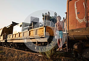 Caucasian man standing in front of a vintage train, gazing out at the picturesque ocean landscape