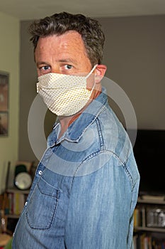 Caucasian man standing indoor home wearing medical protective mask to prevent pandemic disease coronavirus covid-19