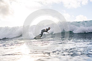 Caucasian man surfing on an ocean wave against a cloudy blue sky
