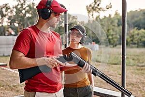 caucasian man teach woman to recharge a rifle on shooting range outdoors