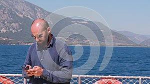 Caucasian man traveler floating on a sea coast yacht rewrites on the phone