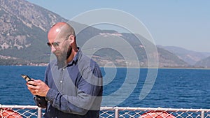 Caucasian man traveler floating on a sea coast yacht rewrites on the phone