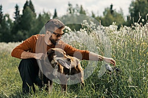 Caucasian man and two dogs in tall grass in rural