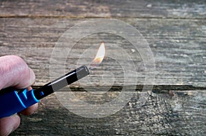 Caucasian man using an electric gas lighter over aged weathered pine wood boards