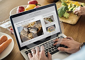 Caucasian man using a laptop in the kitchen searching for recipes