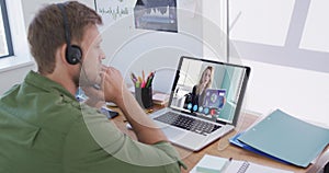 Caucasian man using laptop and phone headset on video call with female colleague