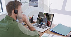 Caucasian man using laptop and phone headset on video call with male colleague