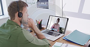 Caucasian man using laptop and phone headset on video call with male colleague